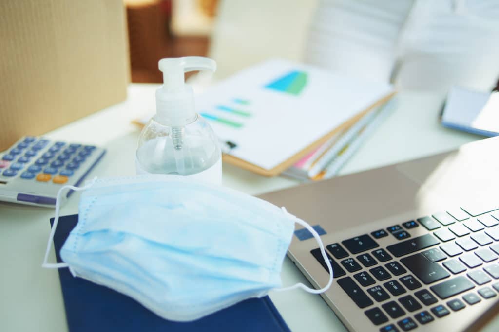 medical mask and hand disinfectant on table in home office medical mask and hand disinfectant on table in home office